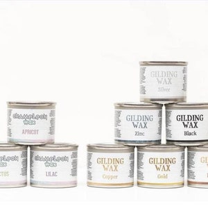 May include: Assortment of 10 small metal tins of wax for gilding and antiquing projects. The tins are labeled with the wax color, including Apricot, Cactus, Lilac, Copper, Gold, Silver, Zinc, Black, and Bronze.