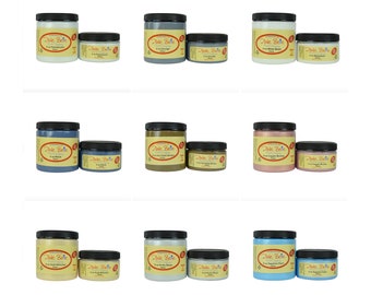 May include: Nine jars of paint in various colors, including white, gray, brown, pink, and blue. The jars are labeled "Dixie Belle" and have a vintage look. The jars are arranged in three rows of three.
