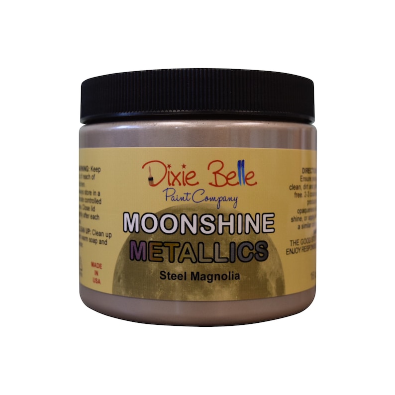 Pode incluir: Um frasco de vidro de tinta Moonshine Metallics da Dixie Belle na cor Steel Magnolia. O frasco tem uma tampa preta e um r&oacute;tulo amarelo com o logotipo da Dixie Belle e o nome do produto.