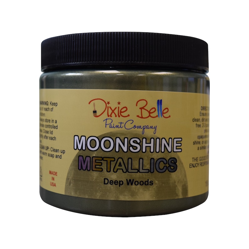 Pode incluir: Um frasco de vidro de tinta Moonshine Metallics da Dixie Belle na cor Deep Woods. O frasco tem uma tampa preta e um r&oacute;tulo amarelo com o logotipo da Dixie Belle e informa&ccedil;&otilde;es do produto.
