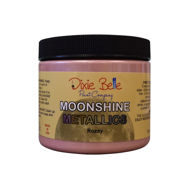Pode incluir: Um frasco de vidro de tinta met&aacute;lica rosa com a etiqueta "Dixie Belle Paint Company Moonshine Metallics Rozay".