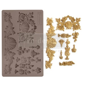 May include: A silicone mold with 15 different designs of ornate floral and shell motifs. The mold is gray and the designs are raised. The mold is for making cake decorations or other edible items.
