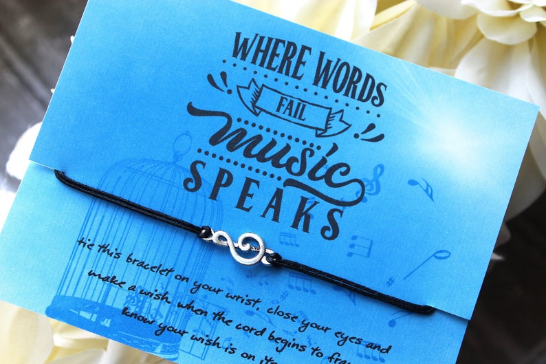 Peut inclure: Un bracelet en cordon noir avec un charme en argent en forme de cl&eacute; de sol. Le bracelet est livr&eacute; avec une carte bleue sur laquelle est inscrit "L&agrave; o&ugrave; les mots &eacute;chouent, la musique parle".