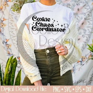 May include: A white t-shirt with black text that reads "Cookie Chaos Coordinator". The text is in a retro font style with stars around it.