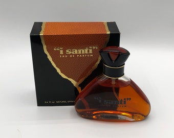 May include: A brown glass bottle of "I Santi" Eau de Parfum with a black cap and a gold label. The bottle is sitting on a white surface. The bottle is 3.4 fl oz and is a natural spray.