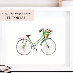 Puede incluir: Pintura a la acuarela de una bicicleta verde con una cesta de flores, enmarcada en un marco blanco. La bicicleta tiene un asiento marrón y detalles en rosa. La imagen incluye el texto "step-by-step video TUTORIAL".