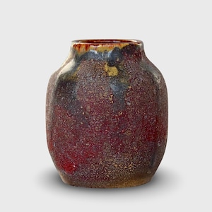 May include: A red, brown, and yellow ceramic vase with a textured surface.