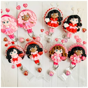 May include: A set of ten Valentine's Day themed badge holders featuring different characters with pink, red, and white accents. Each holder has a clear plastic backing and a metal clip.