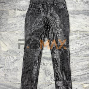 May include: Black faux leather trousers with a crocodile skin texture. The trousers feature a classic five-pocket design, a button and zip closure, and belt loops. The trousers are displayed on a grey surface.