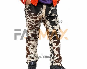 May include: Cowhide-patterned jeans with a mix of black, brown, and white spots. The jeans are worn with black sneakers. The image also shows a glimpse of a jacket and the website address www.fazmax.co.
