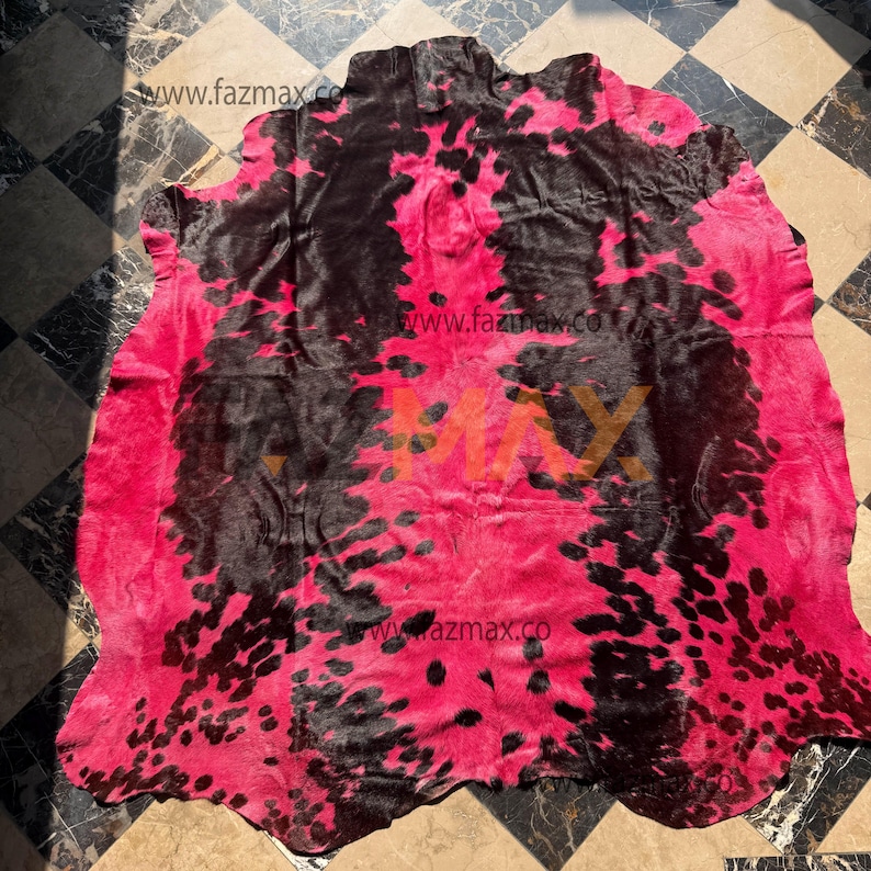 May include: A cowhide rug featuring a striking pink and black spotted design. The rug's natural form and texture are evident, with a predominantly pink background and black spots. This rug is a decorative floor covering, suitable for various interior settings.