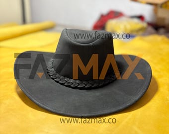May include: A black cowboy hat with a braided band around the crown. The hat has a wide brim and a slightly curved shape. The text "www.fazmax.co" is visible on the hat and in the background.
