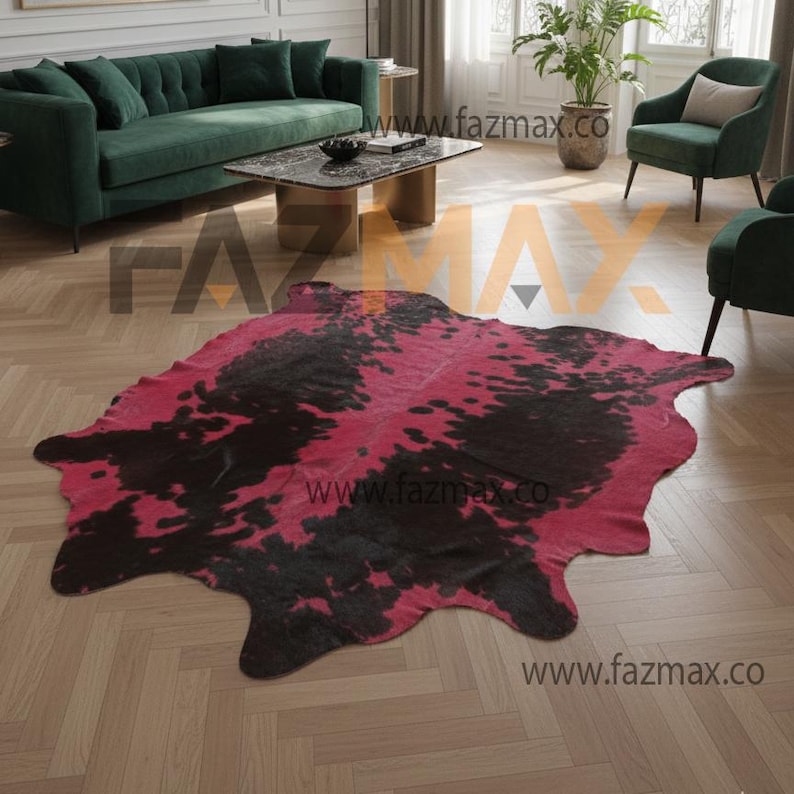 May include: A cowhide rug featuring a bold design of black and cerise pink. The rug has an organic shape and is placed on a wooden floor. The rug is a decorative item in a living room.