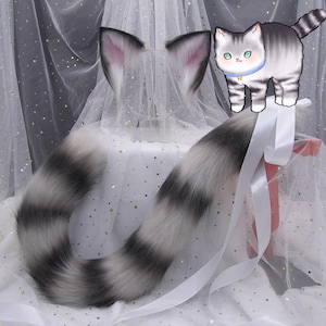 以下が含まれることがあります： 白いリボンが付いた白とグレーの縞模様の猫の尻尾のコスチューム。尻尾は柔らかくふわふわした毛皮で作られており、どんな服装にも遊び心を加えるのに最適です。