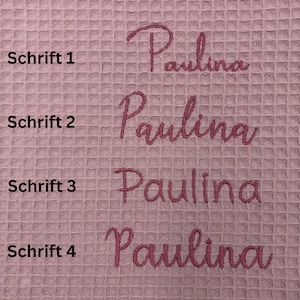 May include: Four different font styles of the name "Paulina" embroidered on a pink waffle weave fabric. The text "Schrift 1", "Schrift 2", "Schrift 3", and "Schrift 4" are written in black to the left of each name.