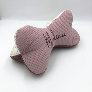 May include: A pink and white waffle-textured pillow with the name "Melina" embroidered in purple.