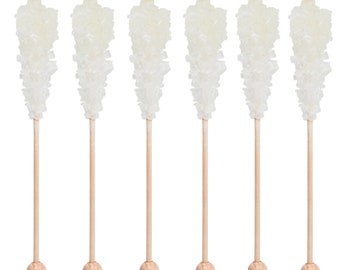 Puede incluir: Seis palitos de caramelo de roca blanco en palitos de madera. El caramelo es transparente y tiene una textura cristalina.