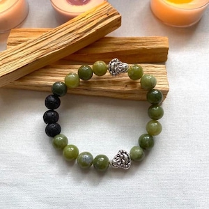 Puede incluir: Un brazalete de cuentas verdes y negras con detalles plateados. El brazalete presenta un degradado de cuentas verdes, con cuentas verde oscuro en un extremo y cuentas verde claro en el otro. El brazalete está adornado con cuentas plateadas y dos dijes plateados.