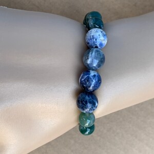 Puede incluir: Un brazalete de piedras preciosas azules y verdes con cuentas redondas. El brazalete est&aacute; hecho de sodalita y aventurina verde.