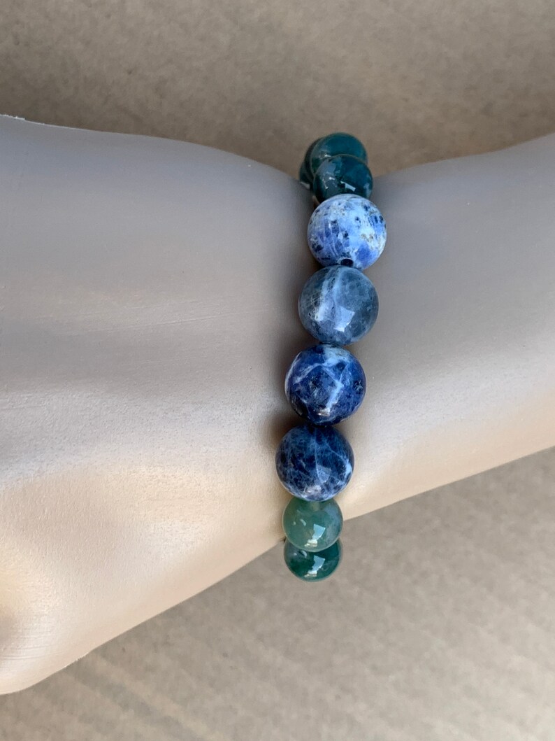 Puede incluir: Un brazalete de piedras preciosas azules y verdes con cuentas redondas. El brazalete est&aacute; hecho de sodalita y aventurina verde.