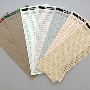 May include: A collection of reading logbooks in various colors, including tan, green, and pink. Each logbook features a black header with the words "READING LOGBOOK" and spaces to record book title and author.
