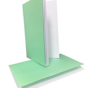 May include: A stack of blank cards with a light green cover and white interior. The cards are folded in half and are ready for writing.