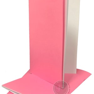 May include: Stack of three pink notebooks with white paper inside. The notebooks are closed and have a smooth, matte finish.