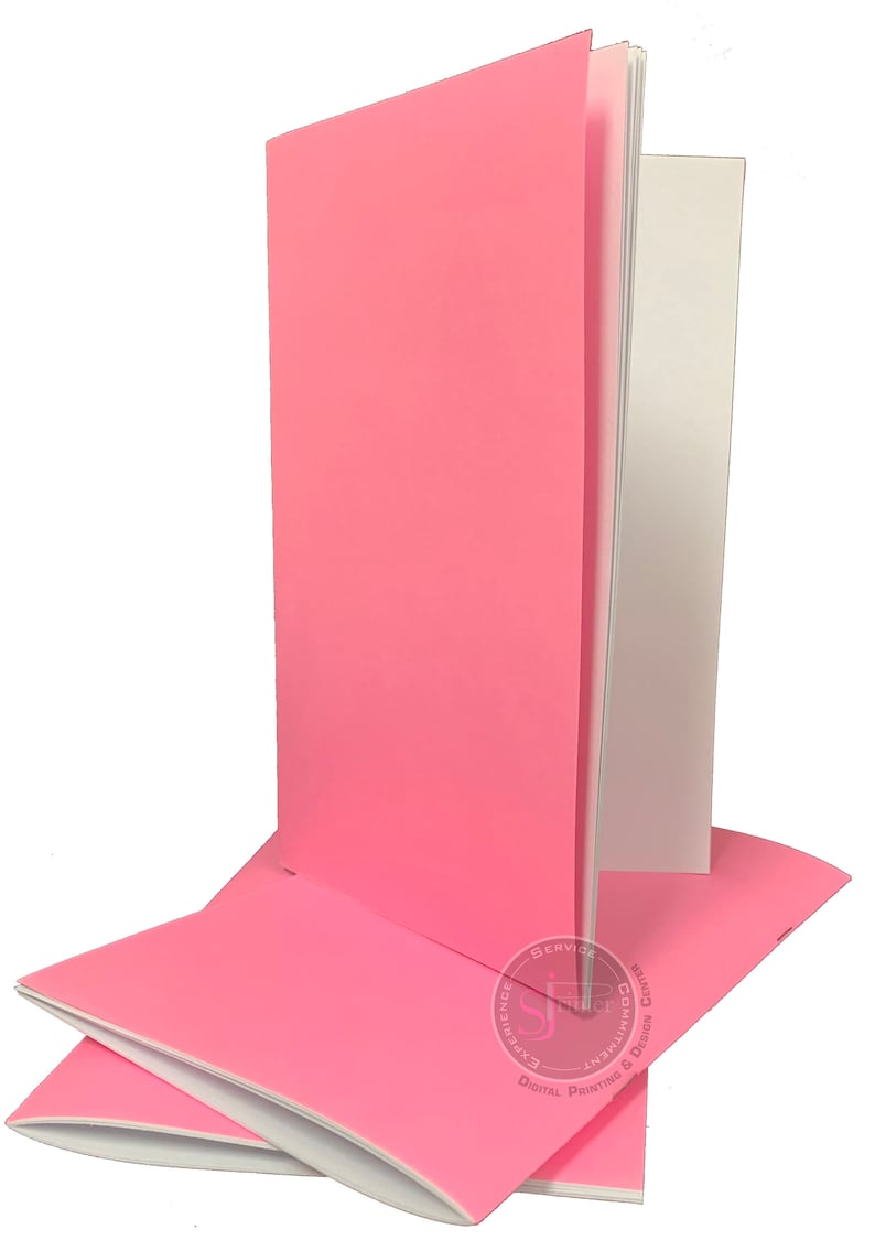 May include: Stack of three pink notebooks with white paper inside. The notebooks are closed and have a smooth, matte finish.