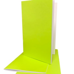 May include: Three lime green notebooks with white spines stacked on top of each other.