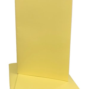 May include: Two yellow notebooks stacked on top of each other. The notebooks are closed and have a white edge.