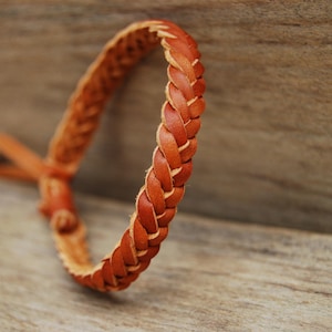 Könnte beinhalten: Ein braunes Lederarmband mit geflochtenem Design.