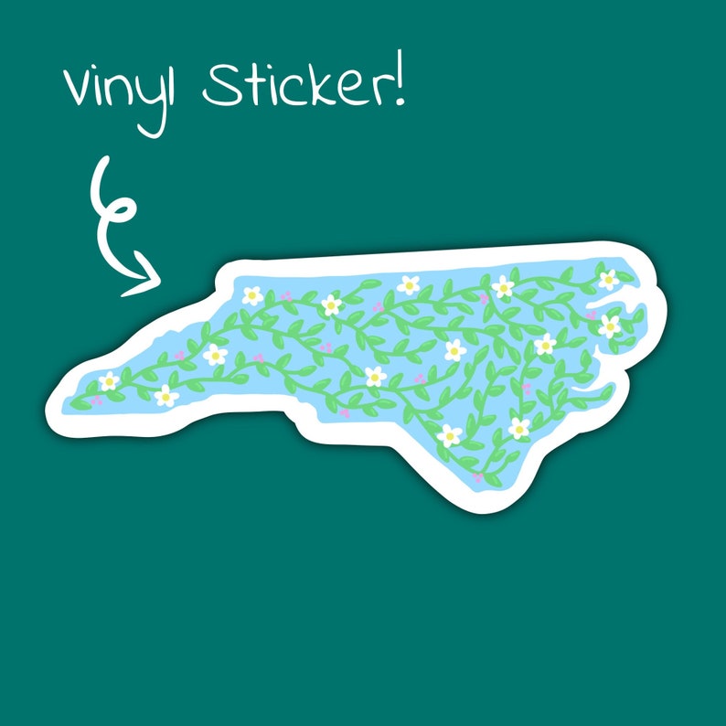 Puede incluir: Una pegatina de vinilo del estado de Carolina del Norte con un contorno azul y flores blancas y enredaderas verdes en el interior. El texto "vinyl sticker!" est&aacute; escrito encima de la pegatina.