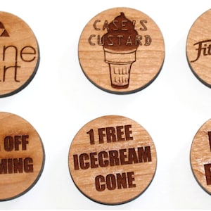 Puede incluir: Seis fichas redondas de madera con varios dise&ntilde;os y textos. Las fichas presentan logotipos para empresas como "Alpine Art", "Case's Custard" y "Fitness First". Otras fichas ofrecen descuentos como "10% de descuento en enmarcar" y "1 cono de helado gratis".