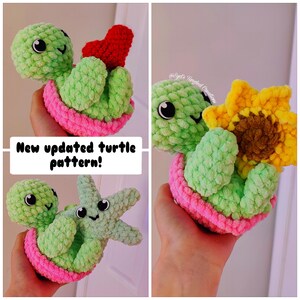 May include: Two crocheted green turtle plushies with pink shells. One turtle is holding a red heart and the other is holding a yellow crocheted sunflower. The caption reads "New updated turtle pattern!"