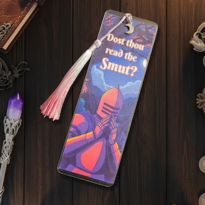 May include: A bookmark with a fantasy illustration of a knight in red and purple armor, with the text "Dost thou read the Smut?" A pink tassel and a silver crescent moon charm are attached.