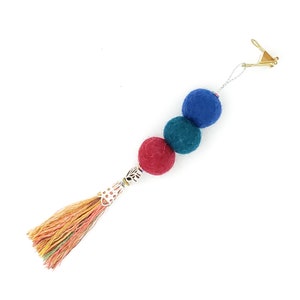 May include: A colorful felt ball keychain with a tassel. The keychain features three felt balls in blue, teal, and red, and a multi-colored tassel.