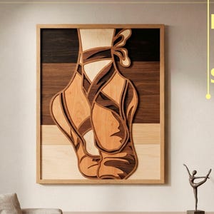 Peut inclure: Une œuvre d'art murale en bois superposé représentant un chausson de danse classique dans des tons de bois clair, moyen et foncé. L'œuvre est encadrée d'un bord en bois clair. Le texte à droite indique DXF AI SVG et en bas DIGITAL CUTTING FILE.