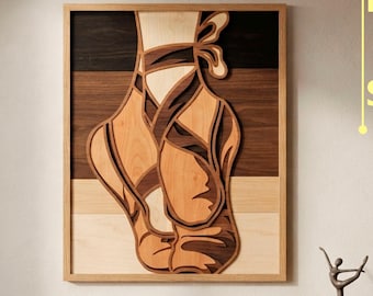 May include: A layered wooden wall art piece depicting a ballet pointe shoe in shades of light, medium, and dark wood. The artwork is framed in a light wood border. Text on the right reads DXF AI SVG and text at the bottom reads DIGITAL CUTTING FILE.