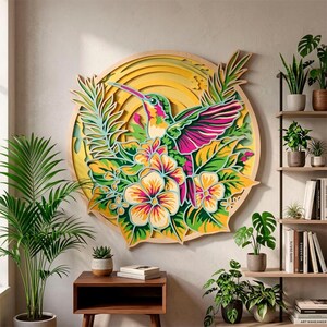 May include: A circular multi-layered wooden wall art piece featuring a hummingbird in flight surrounded by tropical flowers and foliage. The design uses vibrant shades of pink, green, and yellow, with a sunburst pattern in the background.