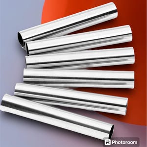 May include: Six shiny, silver metal tubes are arranged diagonally against a gradient background of purple, red, and white. The cylindrical tubes have open ends, reflecting light and creating highlights.