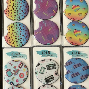 May include: Set of six car coasters with various designs. The coasters feature a leopard print, geometric shapes, a rainbow heart, and retro video game graphics. The coasters are made of a durable material and are perfect for protecting your car's cup holders from spills and scratches.