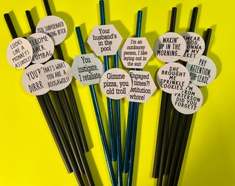May include: A set of 12 black and blue straws with funny sayings attached to them. The sayings include "You're a Boogawolf", "Gimme pizza, you old troll", "She brought me sprinkle cookies", and "I'm from Paterson, did you forget?"