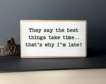 May include: White wooden sign with black text that reads "They say the best things take time... that's why I'm late!"
