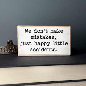 May include: A small wooden sign with the text "We don't make mistakes, just happy little accidents."