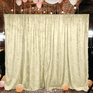 May include: A backdrop made of a cream-colored, textured fabric. The fabric has a subtle shimmer and a slightly wrinkled appearance. The backdrop is hung on a wall and is ready for a photo shoot.