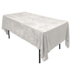 May include: A white crushed velvet tablecloth with a subtle shimmer. The tablecloth is draped over a rectangular table with black legs.