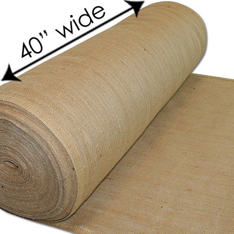 Puede incluir: Se muestra un rollo de tela de yute natural, de 40 pulgadas de ancho (aproximadamente 102 cm). La tela es de color marr&oacute;n claro y tiene un aspecto &aacute;spero y texturizado. El rollo est&aacute; parcialmente desenrollado, revelando el tejido.