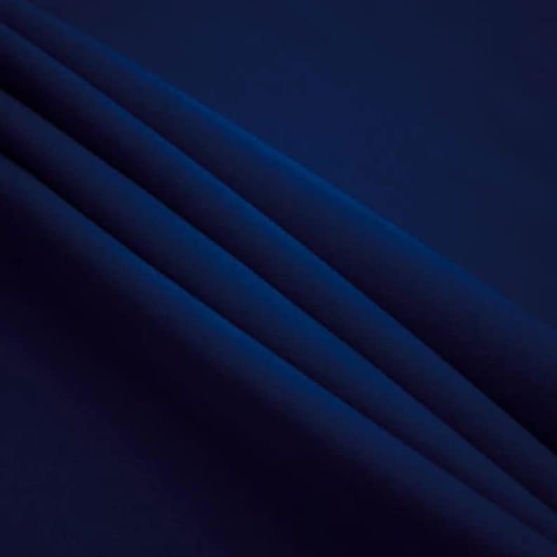 May include: A close-up of a dark blue fabric with soft folds and wrinkles. The fabric has a smooth, even texture.