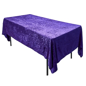 May include: A purple velvet tablecloth with a crinkled texture. The tablecloth is draped over a rectangular table with black legs.