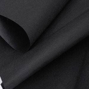 May include: Black non-woven fabric with a textured surface. The fabric is folded in a way that shows the texture and the way it drapes.